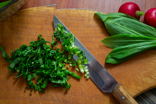 fresh red radish on wooden background with knife and wild leek