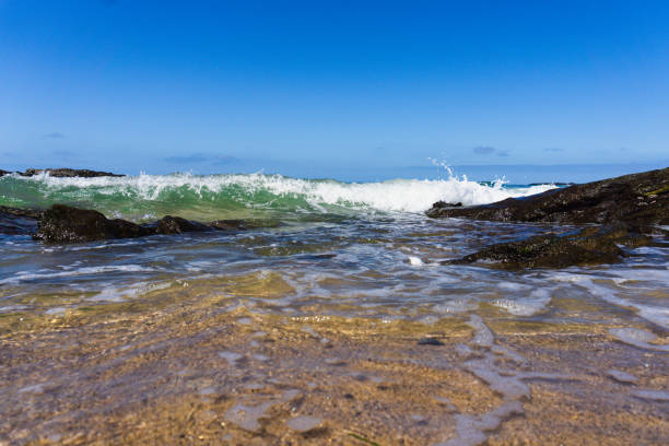 Low angle view of wave rolling onto shallow water of sandy beach