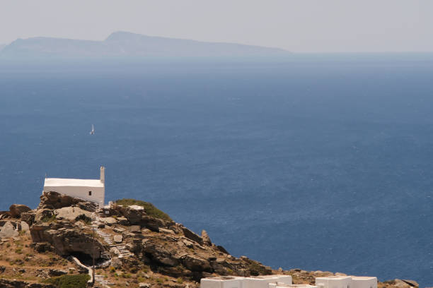 View of a single small whitewashed chapel on ' the top of a hill overlooking the Aegean Sea in Ios Greece