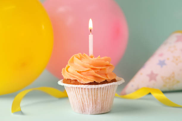 istock Tasty birthday cupcake with candle and party accessories on light blue table. Space for text 1478510800