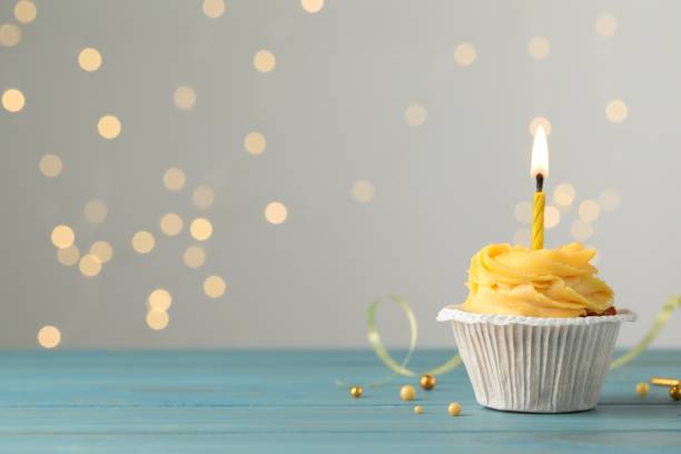 istock Tasty birthday cupcake on light blue wooden table against blurred lights. Space for text 1478511530