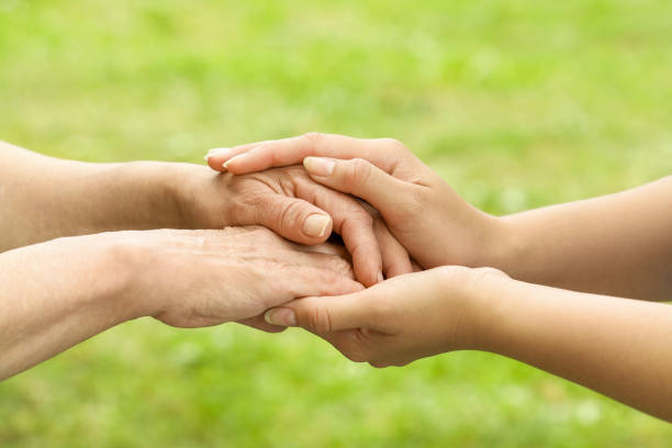 Great grandma and great granddaughter holding hands showing love and affection, close up