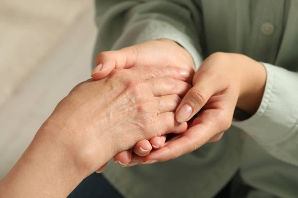 istock Young and elderly women holding hands indoors, closeup 1478512599