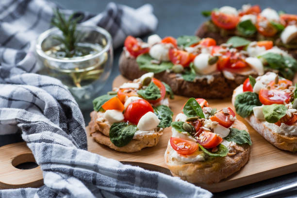 istock Bruschetta (sandwiches) with cherry tomatoes, mozzarella cheese and herbs on a cutting board on a dark background. Traditional Italian snack. 1478520731