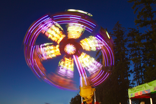 Slow shutter image of a carnival ride spinning in the evening