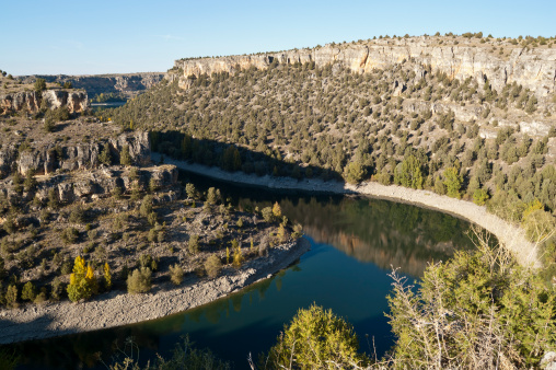 View of Duraton River Canyon. This place is situated in the Hoces del Rio Duraton Natural Park, Segovia Province, Spain. The tree vegetation growing on the slopes of canyon consists of Juniper tree (Juniperus thurifera)