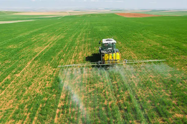 Photo of spraying agricultural lands with a red tractor aerial shot