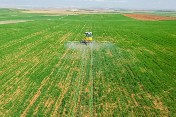 Photo of spraying agricultural lands with a red tractor aerial shot