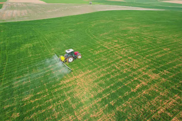 Photo of spraying agricultural lands with a red tractor aerial shot