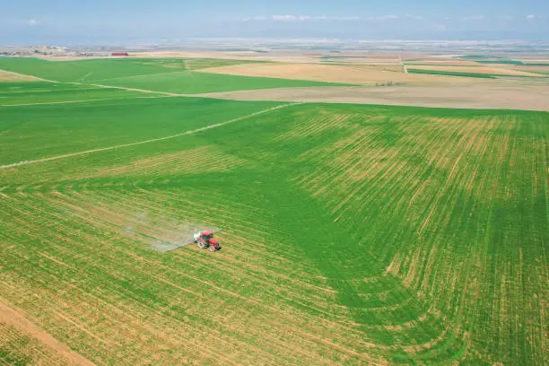 Photo of spraying agricultural lands with a red tractor aerial shot