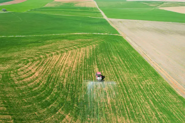 Photo of spraying agricultural lands with a red tractor aerial shot