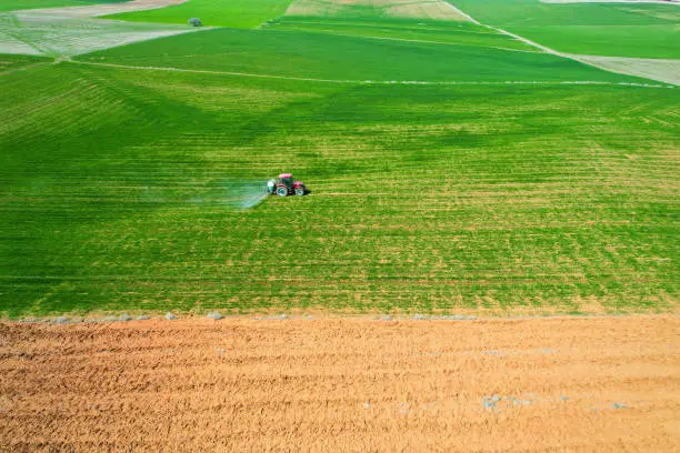 Photo of spraying agricultural lands with a red tractor aerial shot