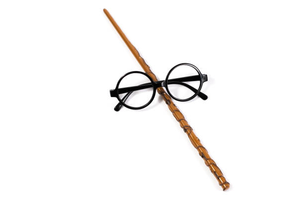 Round black eyeglasses and brown magic wand isolated on white background.