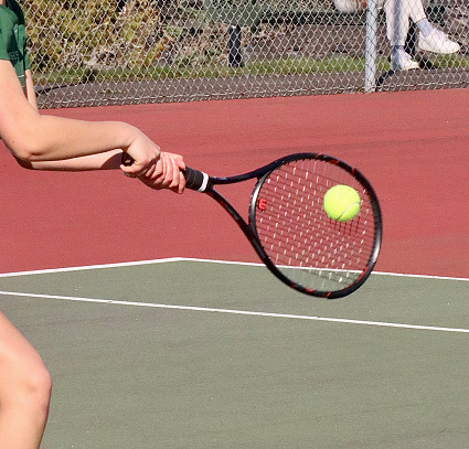 Close-up of a racket hitting a tennis ball in a real match