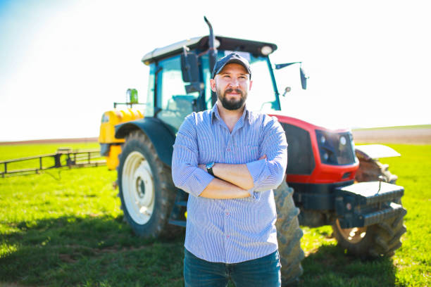 istock happy young farmer with arms folded in front of red tractor 1478534461