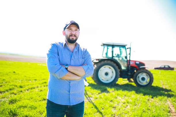 istock happy young farmer with arms folded in front of red tractor 1478534611