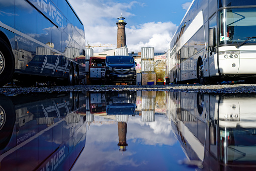 Cologne, Germany April 7 2022: tour buses and vans of a festival on the helios grounds in ehrenfeld are reflected in a puddle