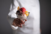 A female chef holding ice cream in a glass cup