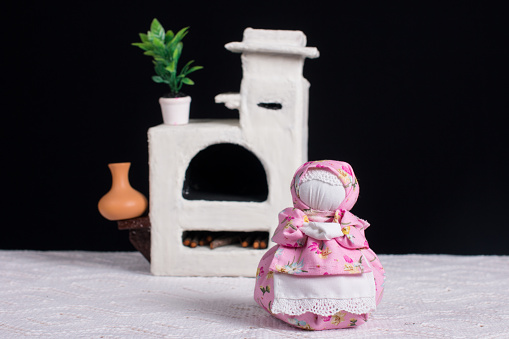 A bouquet of lavender and an oberezhnitsa doll. antique white stove, handmade cloth doll on a black background