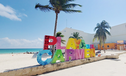 On a sunny day the large Playa Del Carmen letters stand out in with vibrant colors at the beginning of the beach sand on Quinta Avenida.