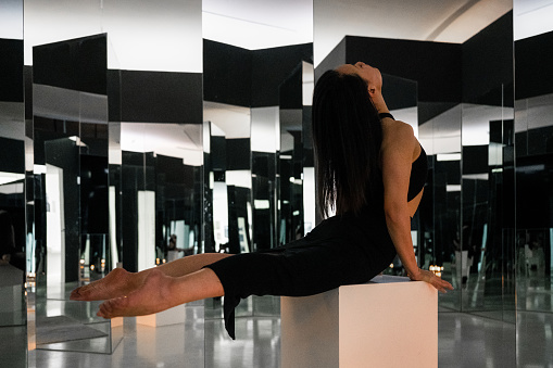 Women in black gym clothes work out in an indoor glass mirror