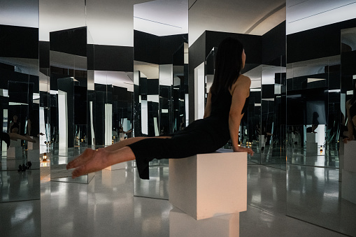 Women in black gym clothes work out in an indoor glass mirror