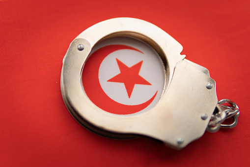 Tunis flag and police handcuffs. The concept of crime and offenses in the country. the concept of crime in the state or government of the country.