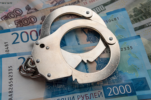 metal handcuffs against the background of the cash currency russian ruble. The concept of bribery or criminal money.