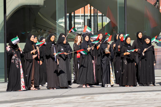 pareja con ropa tradicional y con la bandera nacional de los emiratos árabes unidos al aire libre - flag of the emirates fotografías e imágenes de stock
