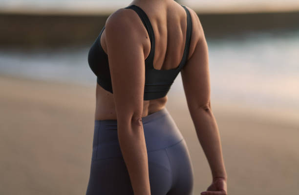 istock Crop anonymous sportswoman stretching back on sandy seashore 1478559287