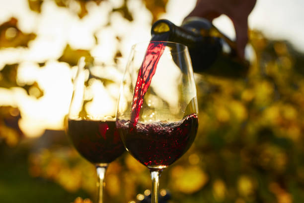 istock Pouring red wine into glasses at sunset 1478559379