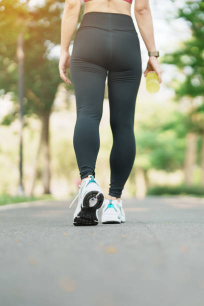 mulher correndo e andando na estrada pela manhã, jovem adulto feminino em sapatos esportivos correndo no parque do lado de fora, músculos das pernas do atleta. exercício, bem-estar, estilo de vida saudável e conceitos de treino - thai cuisine asian cuisine vertical close up - fotografias e filmes do acervo