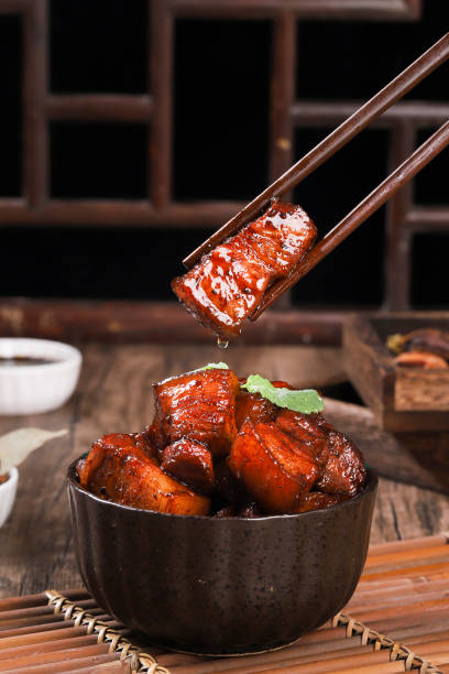 Pork in black bowl at dark slate background. Pork Adobo or Adobong Baboy is sichuhan cuisine dish with braised pork belly, bay leaves, soy sauce, vinegar and spices. Chinese food