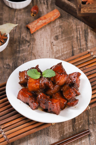 Pork in black bowl at dark slate background. Pork Adobo or Adobong Baboy is sichuhan cuisine dish with braised pork belly, bay leaves, soy sauce, vinegar and spices. Chinese food