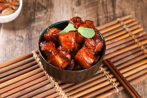 Pork in black bowl at dark slate background. Pork Adobo or Adobong Baboy is sichuhan cuisine dish with braised pork belly, bay leaves, soy sauce, vinegar and spices. Chinese food