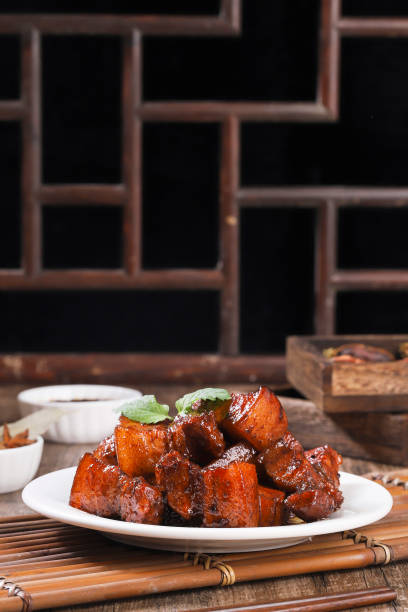 Pork in black bowl at dark slate background. Pork Adobo or Adobong Baboy is sichuhan cuisine dish with braised pork belly, bay leaves, soy sauce, vinegar and spices. Chinese food