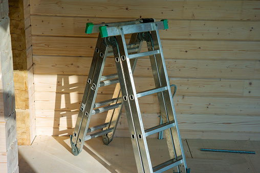 a foldable metal ladder inside a room with wooden walls, indoor shot