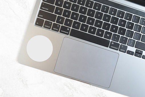 Closeup of modern laptop with a white round sticker taken from a high angle view. Contains clipping path around the sticker to make it easy to add your design to the sticker.