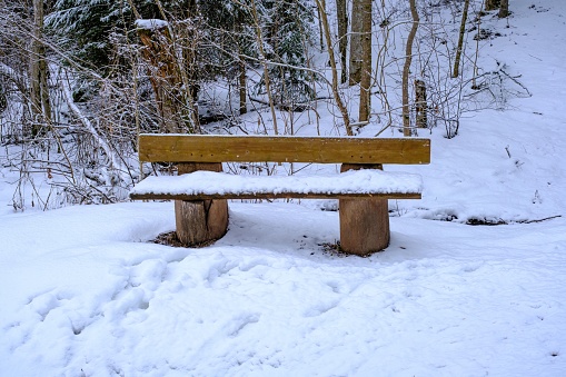 A snowy wooden bench in the winter landscape.