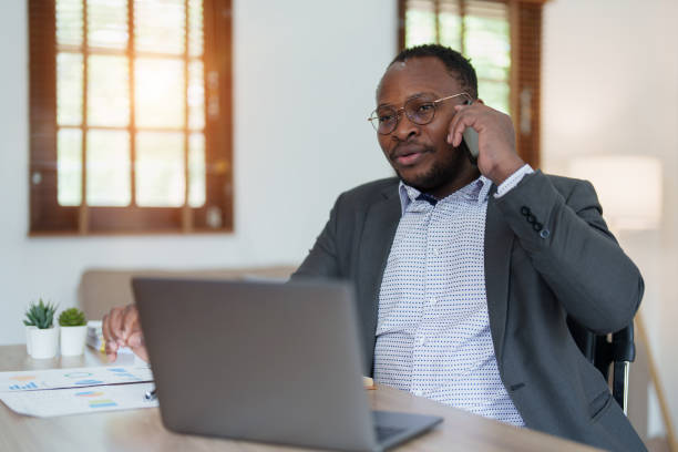 istock middle aged man American African using smart phone mobile and laptop computer with planning working on financial document, tax, exchange, accounting and Financial advisor 1478640686