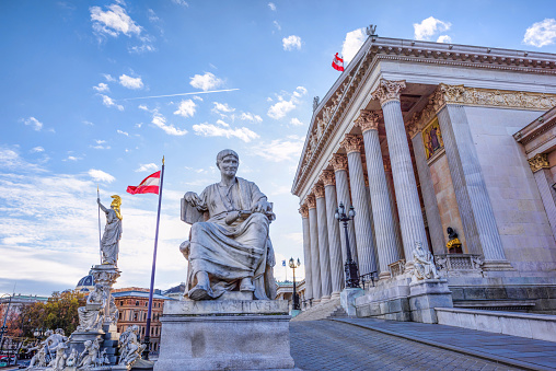 Roman statue at historic building of the Austrian parliament in Vienna, on ringstrasse street, Austria, sunny day and blue sky