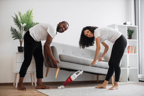 istock Woman using vacuum for cleaning under couch that lifting man 1478651412