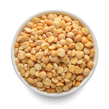 Dried yellow peas in white bowl isolated on white background. Top view.