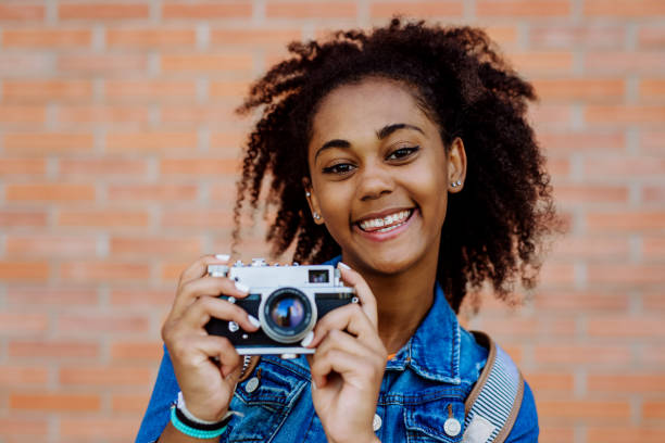 istock Multiracial girl standing in front of brick wall with camera, and posing. 1478653967