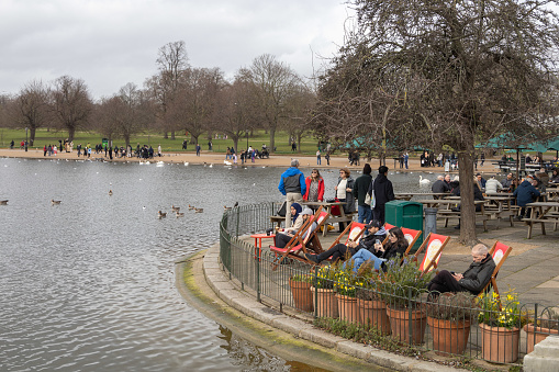 Hyde Park London, people sitting by the late at the Serpentine Bar and Kitchen, outdoor cafe in the springtime