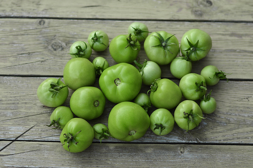 Green tomato on wooden background. Raw green tomato on table for dinner