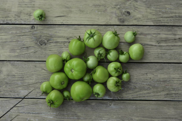 istock Green tomato on wooden background. Raw green tomato on table for dinner 1478663300