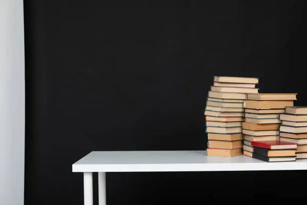 stack of books on white table in the library on a black background