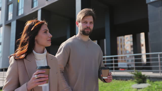 Young couple smiling confident drinking coffee at street. Man and woman having conversation on urban street.