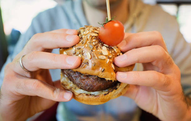 istock a man holds a burger in his hand 1478669050